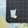 Macro shot of 2cm blue resin lemonade charm with ruler on a black grid cutting mat - Blue Lemon Tea
