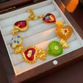 Makroaufnahme von bunten Emaille-Herzanhängern an einem Vintage-Goldarmband in einer Box - Armband-Gold-Mehrfarbig