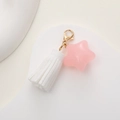 Detailed view of a pink star pendant and white tassel on a gold lobster clasp keychain - White with Pink Star