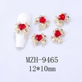 Macro detail of golden alloy bow nail charm with red heart zircon measuring 12x10mm - Gold Base Red Heart (9465)