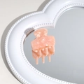 Macro detail of a pale peach acetate hair claw clip reflected on a heart-shaped mirror - Orange