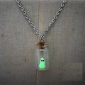 Collana con piccolo fantasma verde fluorescente in bottiglia di vetro su busto beige - Collana Verde