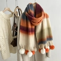 Detailed close-up of mohair rainbow striped scarf with large decorative fluffy pom-poms - Orange