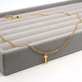 Detail shot of a gold stainless steel letter I pendant necklace on a grey velvet tray - Letter I / Gold