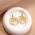 Macro shot of gold hollow spiral rose dangle earrings on a textured white tray - Ear Hook - Gold
