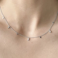 Detailopname van zilveren kwastjesketting met druppelhangers op het sleutelbeen - Zilver