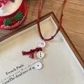 Détail du collier bonhomme de neige avec cordon en cuir rouge et pompon sur tissu - Cordon en Cuir Marron Écharpe Rouge Style Bonhomme de Neige