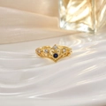Macro shot of a gold crown ring featuring a deep blue gemstone and small diamonds on white fabric - Deep Blue Stone Crown (JZ0135C)