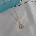 Macro shot of gold teardrop pendant with white mother of pearl and crown detail - Teardrop Crown Shell Pendant