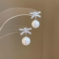 Detailed view of silver bow-shaped earrings with sparkling cubic zirconia and white pearl drop - 39# Silver Needle-Silver Bow Pearl