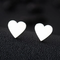 Macro shot of polished silver heart-shaped stainless steel earrings on black leather - Heart / Silver