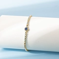 Detalle de la pulsera bañada en oro de 18K con gema azul redonda y cristales de circón - Septiembre / Zafiro
