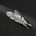 Macro shot of silver feather brooch with crystal rhinestones on a black background - Feather Silver