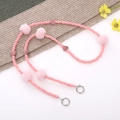 Detail von rosa Samtperlen und weichen Pelzkugeln an einem Taschengurt mit Clips - Rosa