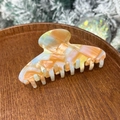 Détail de la pince à cheveux en acétate marbré orange avec lettrage doré sur plateau - Mélange Orange Vert - 8 Dents