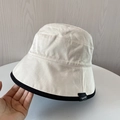 Detail shot of a beige cotton bucket hat featuring black trim and a small woven side label - M(56-58cm) / Beige
