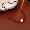 Detalle de collar de cuentas rojas con colgante de perla sobre un plato de cerámica blanca - Rojo (Chapado en oro real)