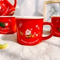 Festive red ceramic Christmas mugs featuring Santa and reindeer designs in a cozy home setting - A Sleigh