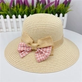 Close-up of a woven straw sun hat featuring a pink and white checkered ribbon bow - Beige
