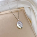 Dettaglio di una collana in acciaio al titanio argento con ciondolo ovale a rosa in rilievo - Acciaio al titanio / Argento