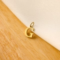 Macro shot of a golden letter G pendant on a minimalist wood and white fabric background - 14k Letter - G (letter Height 1cm)