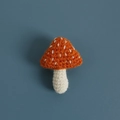 Handmade crochet mushroom brooch featuring an orange cap with white dots on gray background - Orange Mushroom Brooch