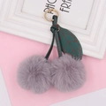 Close-up of gray faux fur cherry plush keychain with green faux leather leaf and gold ring - Spring Ring / Light Gray