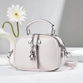 Close-up of white lychee grain PU leather texture with silver tassel and bear charm - Off White