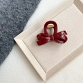 Macro detail of wine red bow hair claw clip with golden spring on a beige textured tray - Wine Red - Irregular Bowknot Claw