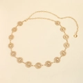 Détail d'une ceinture chaîne dorée élégante avec des médaillons ronds sur fond beige - Pièce Ronde / 19292 Or