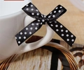 Close-up of black satin ribbon bow with white polka dots on a white ceramic mug handle - Black
