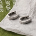 Pendientes minimalistas de cobre plateado en forma de U sobre fondo de papel blanco - Plateado
