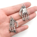 Silver skeleton hand metal charms for Halloween jewelry DIY, shown in hand for scale - Extra Long Skeleton Hand 37x22mm