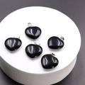 Polished black agate heart pendants with silver metal clasps on a white pedestal - Obsidian