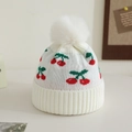 Close-up of white knitted baby beanie with red cherry embroidery and soft pom-pom detail - 1-3 Years / White