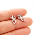 Macro detail of silver stainless steel lizard stud earrings showing scale and polished finish - Steel