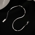Minimalist silver stainless steel flat snake chain anklet with lobster clasp on black background - Silver