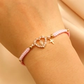 Pink woven bracelet detail featuring golden Virgin Mary heart and cross pendants - KC Gold Pink Rope (G-309)