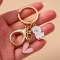 Cartoon dog and pink heart metal keychain with gold plating on a hand palm - Heart Lamb