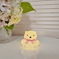 Cute bear night light with yellow glow and pink ribbon on a cozy white desk - Small Bear - Pink