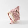 Detail of pink knitted baby hat featuring delicate lace trim and a contrast bow accent - 6-24 Months / Pink