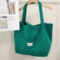 Detail of green canvas tote bag featuring an outer pocket with woven brand label - Mint Green