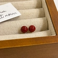 Macro view of minimalist red pearl stud earrings resting in a premium wooden jewelry box - Real Gold Plated / 8mm / Red