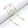 Detalle de cadena dorada con colgantes de corazón y perlas sobre soporte blanco - Diseño de Corazón