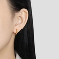 Minimalist gold plated stainless steel twisted hoop earrings worn on a model's ear - Gold Style