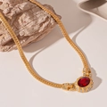 Dettaglio di una collana a catena dorata vintage con gemma ovale rossa e strass lucidi - Catena di Serpente con Strass Ovali Rossi