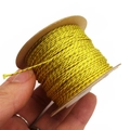 Macro shot showing 1mm gold braided thread thickness on a kraft paper spool - Yellow