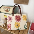 Detail der floralen Canvas-Tasche mit braunen Ledergriffen und einem Metalldruckknopf - Blume