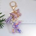 Purple glitter resin letter K keychain with butterfly charm and soft tassel on gold clasp - Letter K