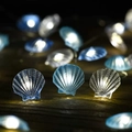 LED scallop shell string lights with warm white glow on a rustic dark wood surface - Seashell (3-Color Mixed)
